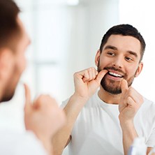 man flossing in front of a mirror