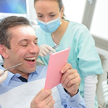 patient with dental implants admiring his smile in a mirror