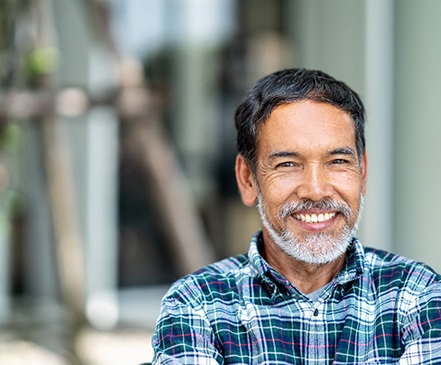 Man in plaid shirt smiling outside
