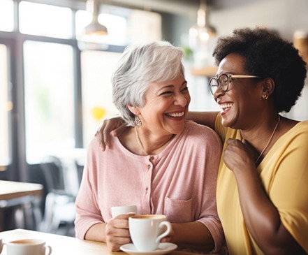 Two friends smiling while drinking cup of coffee