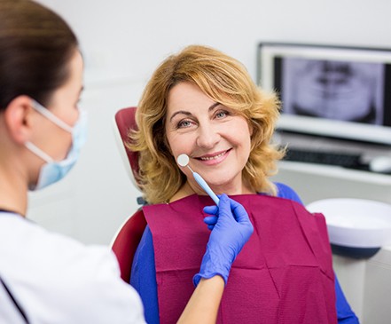 Older woman at the dentist’s office learning about dentures in Spring