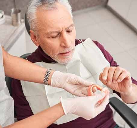 a dentist showing a patient how his new dentures work