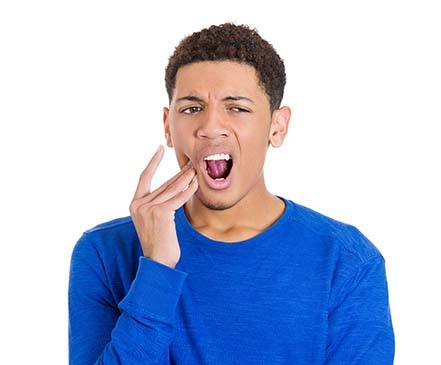 Man touching his cheek due to dental emergency