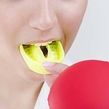 Woman placing a custom mouthguard into her mouth