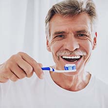 Older man holding a toothbrush and smiling