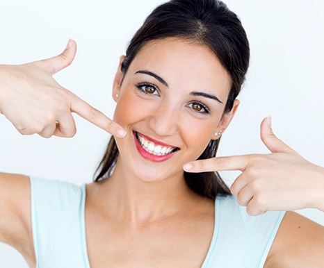 young woman pointing to her smile with straight white teeth 