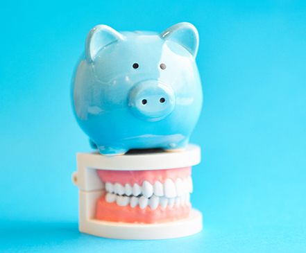 Piggy bank and teeth representing the cost of Invisalign in Spring