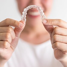 Spring cosmetic dentist smiling and holding up Invisalign aligners