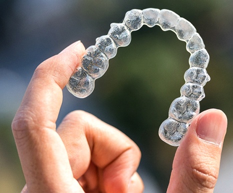 person holding Invisalign aligners