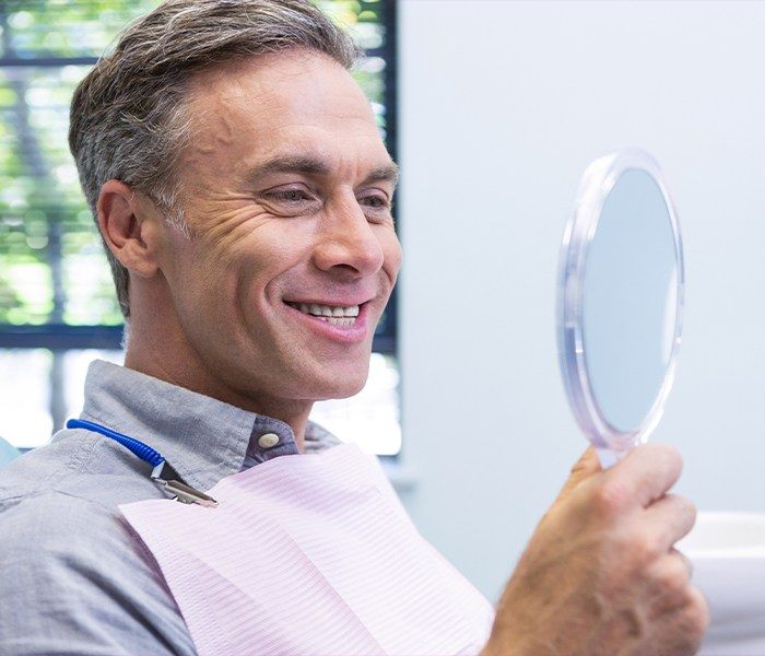 Man looking at dental bridge in mirror