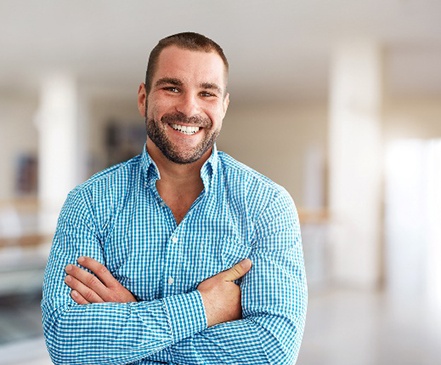 Man in blue button-up shirt smiling with veneers