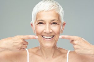 a woman smiling and pointing to her straight smile