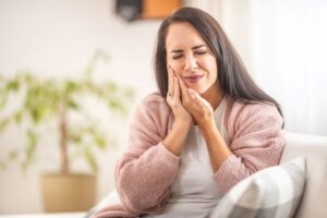 Woman sitting on sofa, suffering from a toothache